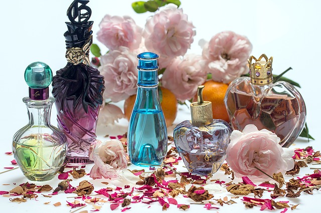 шишенца с парфюми на фона на различни цветя