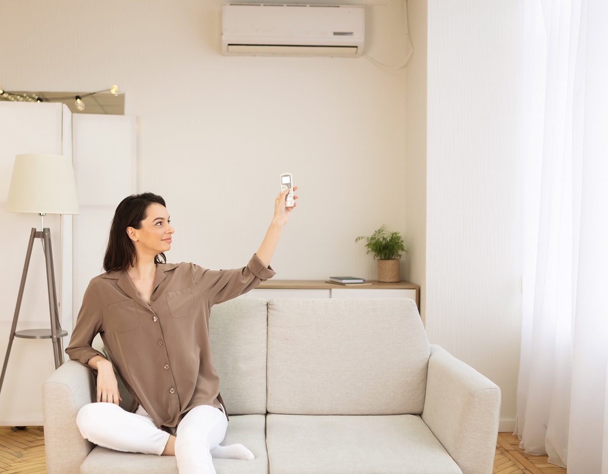 млада жена настройва климатика от дивана